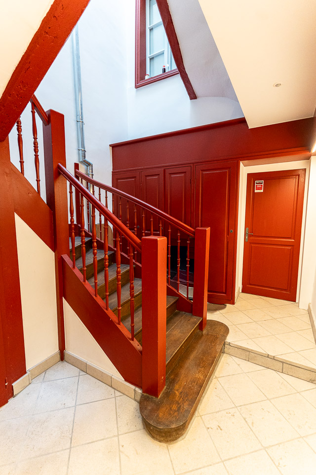 Escalier en bois rouge dans un hall d'entrée rénové