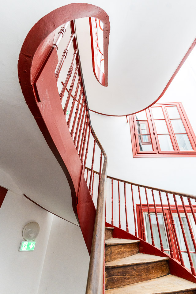 Cage d'escalier à garde-corps rouge sous lumière naturelle