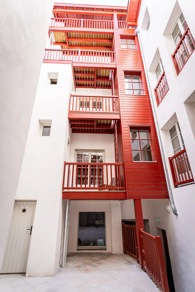 Cour intérieure réhabilitée avec balcons et menuiseries rouges