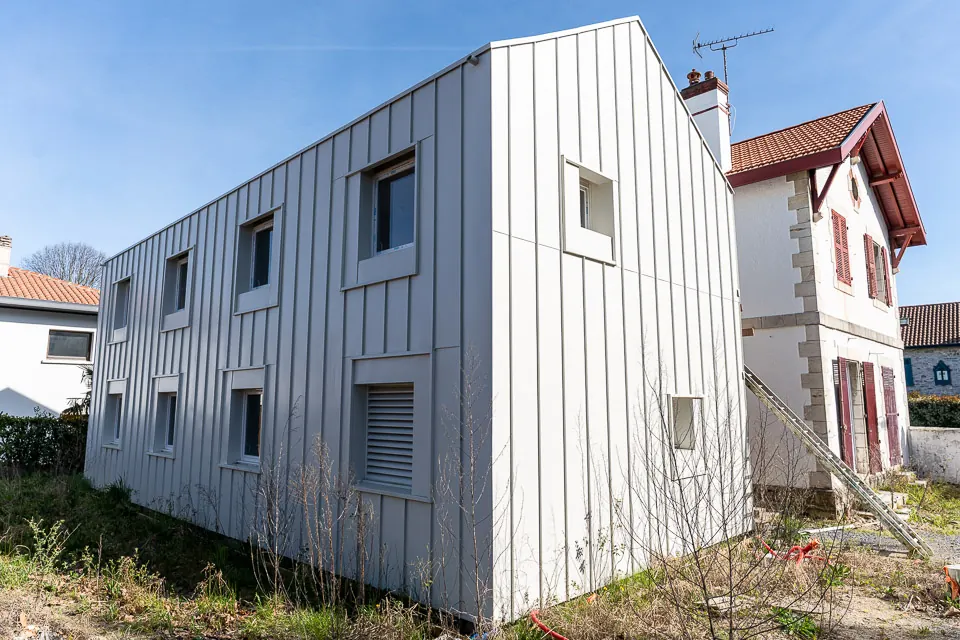 Extension contemporaine en bardage métallique accolée à une maison basque